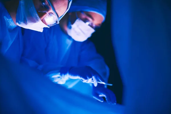 Equipe de médicos em cirurgia em um fundo escuro. — Fotografia de Stock