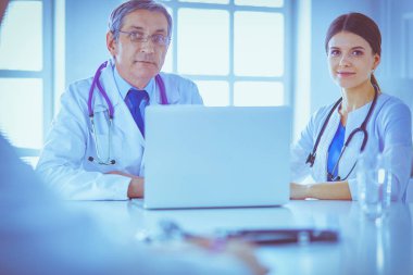 Parlak bir ofiste çalışan ciddi bir tıbbi ekip.