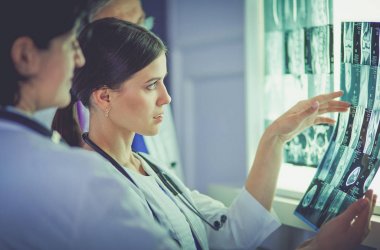 Bir grup doktor bir klinikte röntgenleri inceliyor, teşhis koymayı düşünüyorlar.