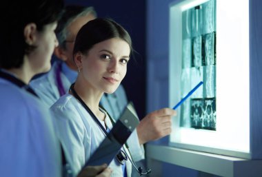 Bir grup doktor bir klinikte röntgenleri inceliyor, teşhis koymayı düşünüyorlar.