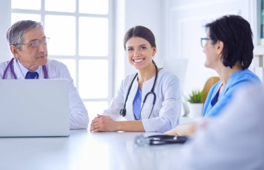 Ciddi bir tıbbi ekip hastaları parlak bir ofiste tartışıyor.