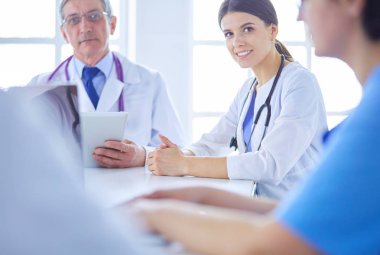 Ciddi bir tıbbi ekip hastaları parlak bir ofiste tartışıyor.