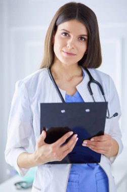 Kadın doktor hastanede dosyayla bekliyor.