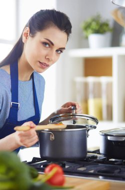 Mutfakta ahşap kaşıkla yemek pişiren kadın