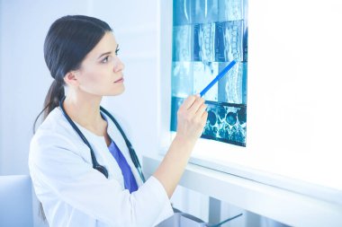 Stetoskop lu genç gülümseyen kadın doktor doktor ofisinde röntgeni işaret ediyor