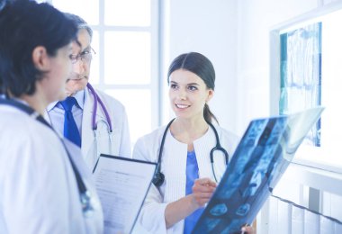 Hastanedeki röntgenlere bakarak hastaların teşhisini tartışan gülümseyen doktorlar