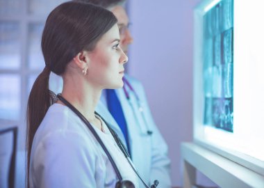 Bir grup doktor bir klinikte röntgenleri inceliyor, teşhis koymayı düşünüyorlar.