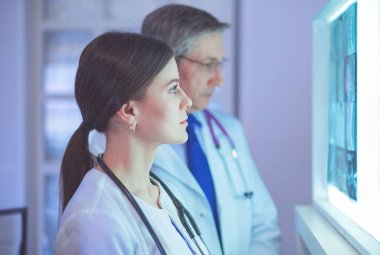 Bir grup doktor bir klinikte röntgenleri inceliyor, teşhis koymayı düşünüyorlar.