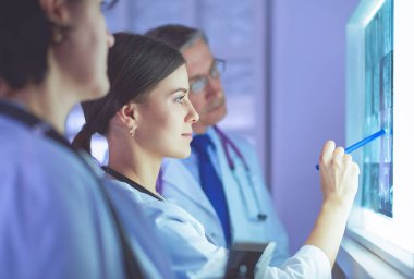 Bir grup doktor bir klinikte röntgenleri inceliyor, teşhis koymayı düşünüyorlar.
