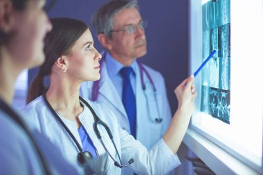 Bir grup doktor bir klinikte röntgenleri inceliyor, teşhis koymayı düşünüyorlar.