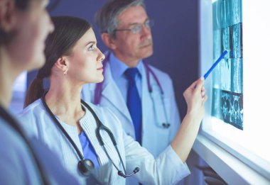 Bir grup doktor bir klinikte röntgenleri inceliyor, teşhis koymayı düşünüyorlar.