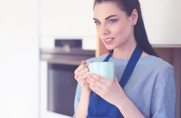 Portrait of young woman with cup against kitchen interior background — Stock Photo, Image