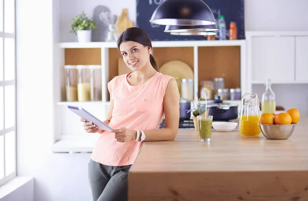 Vacker ung kvinna med hjälp av en digital tablett i köket — Stockfoto