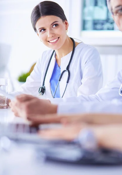 Lächelnde Ärztin mit einem Laptop, die mit ihren Kollegen in einem hellen Krankenhauszimmer arbeitet — Stockfoto