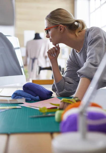 Junge attraktive Modedesignerinnen lehnen am Schreibtisch im Büro und arbeiten mit einem Laptop — Stockfoto