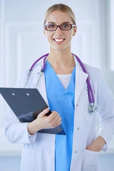 Médecin souriante avec un dossier en uniforme debout — Photo