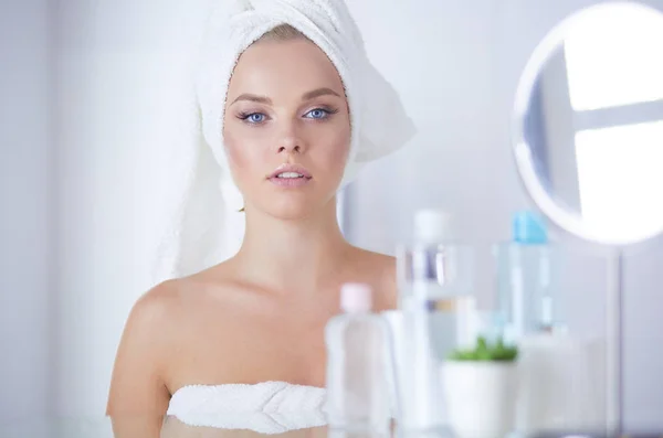 Giovane donna in accappatoio guardando nello specchio del bagno — Foto Stock