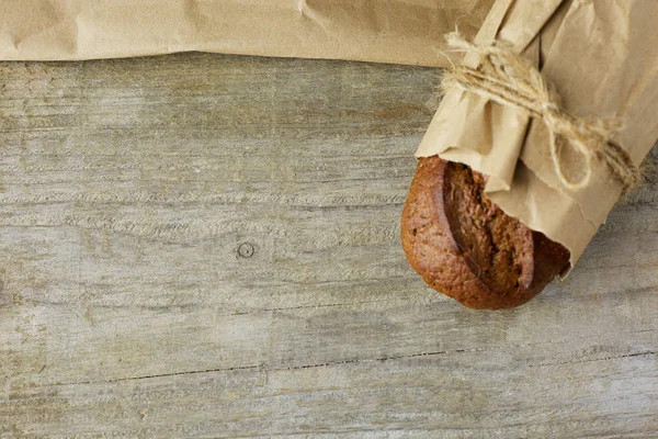 Panes de pan rústico recién horneados en bolsas de papel sobre fondo de madera oscura —  Fotos de Stock