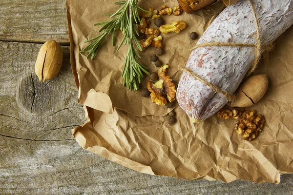 Французская салями и грецкие орехи на бумаге на деревянном фоне — стоковое фото