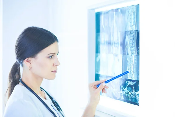 Giovane medico femminile sorridente con stetoscopio che punta ai raggi X presso lo studio medico — Foto Stock