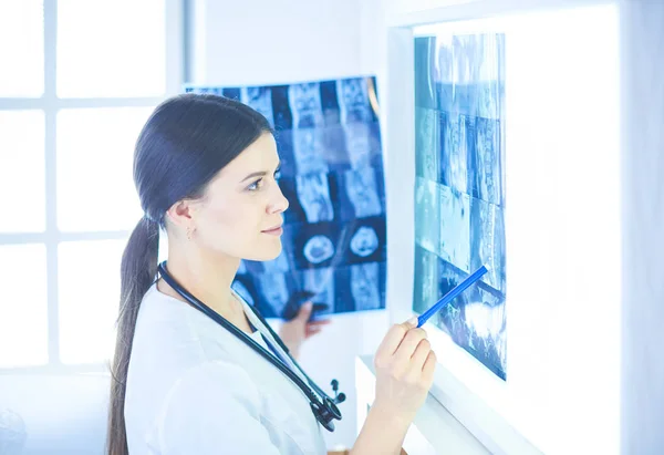 Jeune femme médecin souriante avec stéthoscope pointant vers la radiographie au cabinet des médecins — Photo