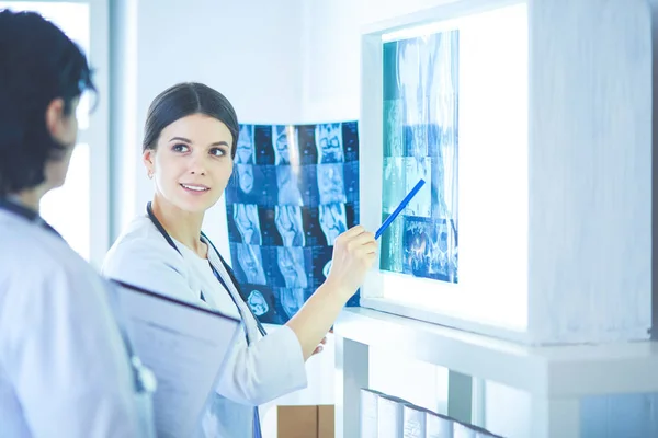 Dua dokter tersenyum menunjuk x-ray di ruang konsultasi rumah sakit — Stok Foto