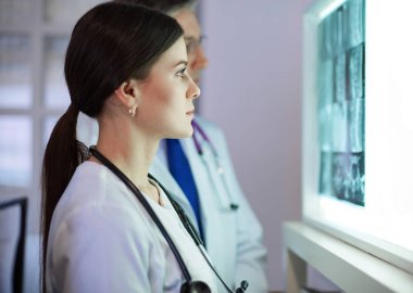 Bir grup doktor bir klinikte röntgenleri inceliyor, teşhis koymayı düşünüyorlar.