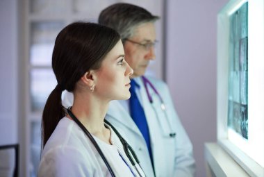 Bir grup doktor bir klinikte röntgenleri inceliyor, teşhis koymayı düşünüyorlar.