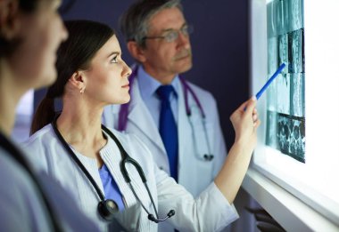 Bir grup doktor bir klinikte röntgenleri inceliyor, teşhis koymayı düşünüyorlar.