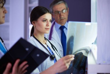 Bir grup doktor bir klinikte röntgenleri inceliyor, teşhis koymayı düşünüyorlar.