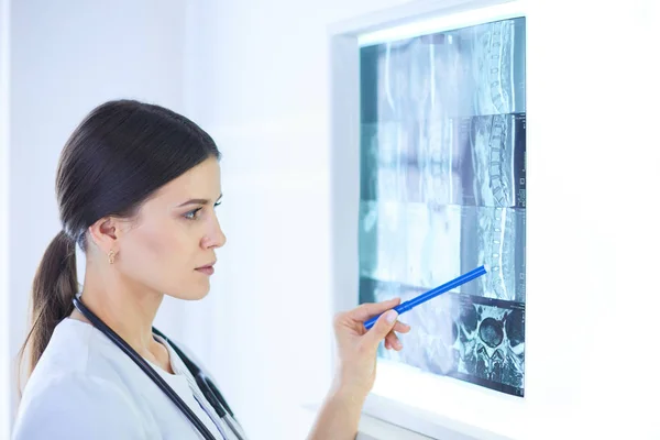 Young smiling female doctor with stethoscope pointing at X-ray at doctors office — Stock Photo, Image