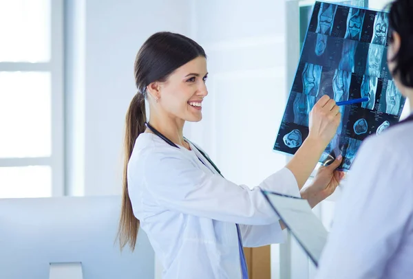 Two smiling doctors pointing at x-rays in a hospital consulting room