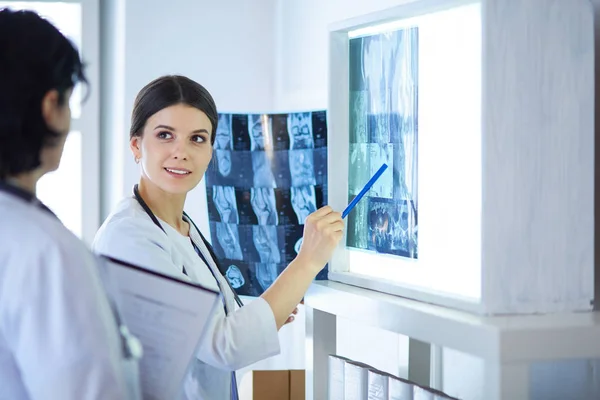 Két mosolygó orvos röntgenre mutat egy kórházi rendelőben. — Stock Fotó
