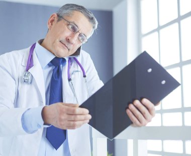 Erkek doktor hastanedeki panoya notlar yazıyor.