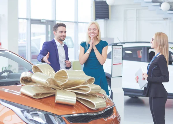 Een man maakt een geschenk - een auto aan zijn vrouw. Ze is hier verbaasd over. Ze zijn hier erg blij mee. — Stockfoto