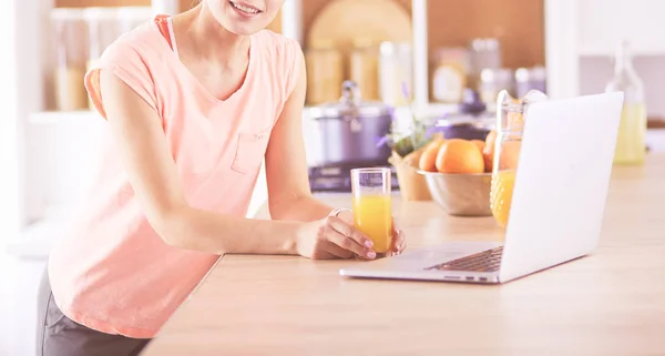 Młoda kobieta w kuchni z laptopem szuka receptur, uśmiechnięta. Koncepcja blogerki żywności — Zdjęcie stockowe