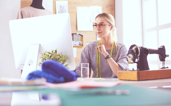 Jonge vrouw met behulp van laptop mode ontwerper werken in de achtergrond in de studio — Stockfoto