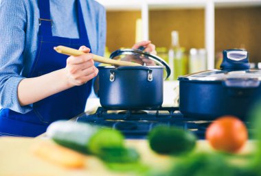 Mutfakta ahşap kaşıkla yemek pişiren kadın