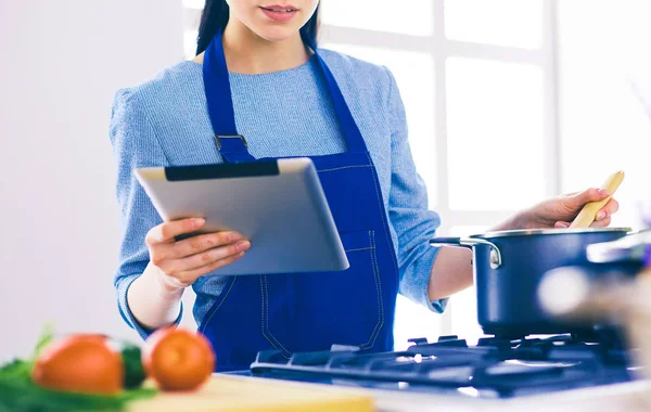 Junge Frau kocht mit Tablet-Computer in ihrer Küche — Stockfoto