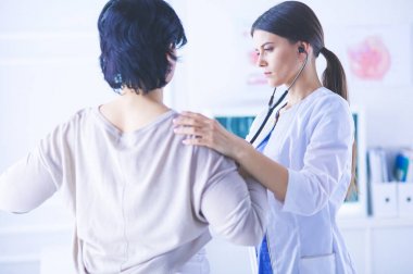 Steteskoplu bir hastayı dinleyen bir kadın doktor.