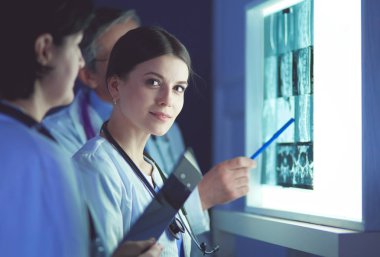 Bir grup doktor bir klinikte röntgenleri inceliyor, teşhis koymayı düşünüyorlar.