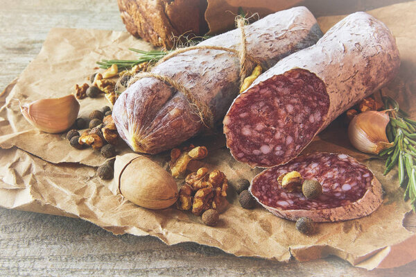 French salami and walnuts on craft paper on wooden background