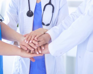 Bir grup doktor ellerini birleştiriyor. Yakın plan.