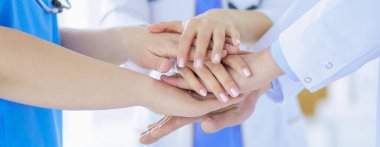 Bir grup doktor ellerini birleştiriyor. Yakın plan.