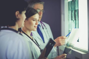 Bir grup doktor bir klinikte röntgenleri inceliyor, teşhis koymayı düşünüyorlar.