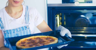 Mutlu genç bayan evde pizza pişiriyor.