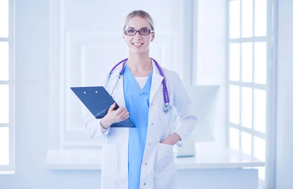 Médica sorridente com uma pasta em pé uniforme — Fotografia de Stock