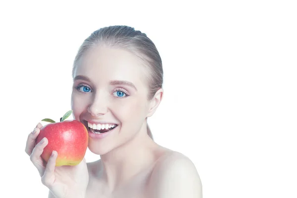 Portrét šťastné usmívající se mladé krásné ženy pojídáním červeného jablka, přes bílé pozadí — Stock fotografie