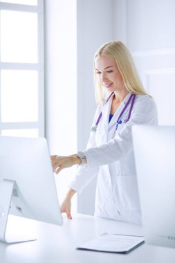 Hastane ofisindeki bilgisayara işaret ederken iş yerindeki genç kadın doktor.