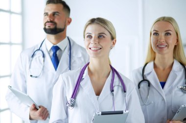 Gülümseyen doktorlar çalışırken bir arada duruyorlar.